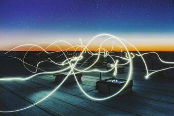 A long exposure image capturing vibrant light trails painted across a rooftop at night.